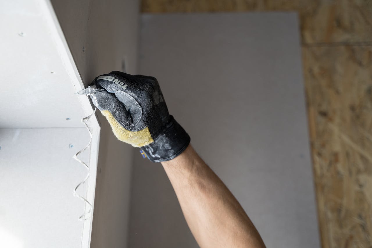 Close-up of a gloved hand applying plaster to a wall indoors in Falun, Sweden.
